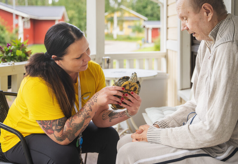 Ykköskodin ohjaaja ja asukas istumassa yhdessä ja tutkimassa kilpikonnaa