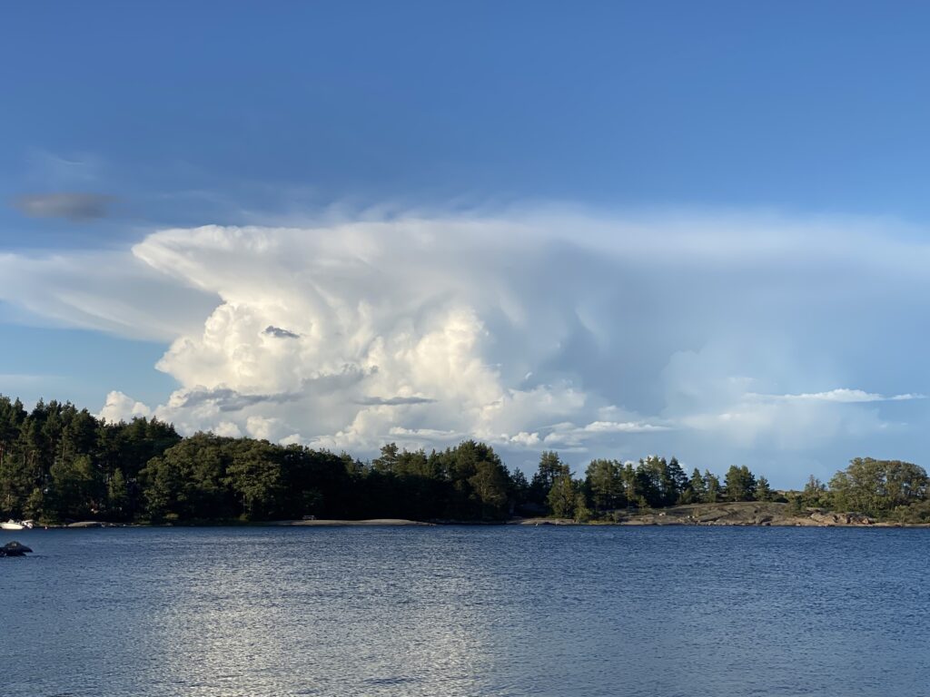 Maisemakuva suomen luonnosta. Järvi ja sininen taivas, jossa pilviä.
