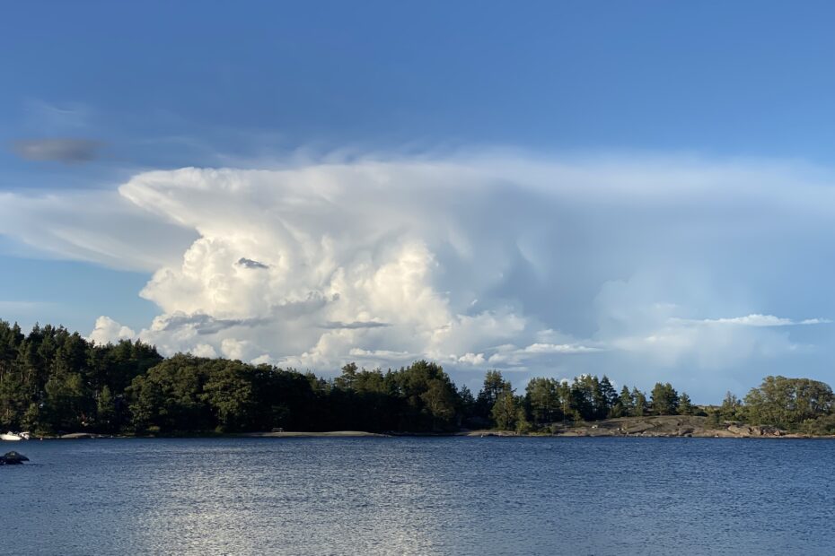 Maisemakuva suomen luonnosta. Järvi ja sininen taivas, jossa pilviä.
