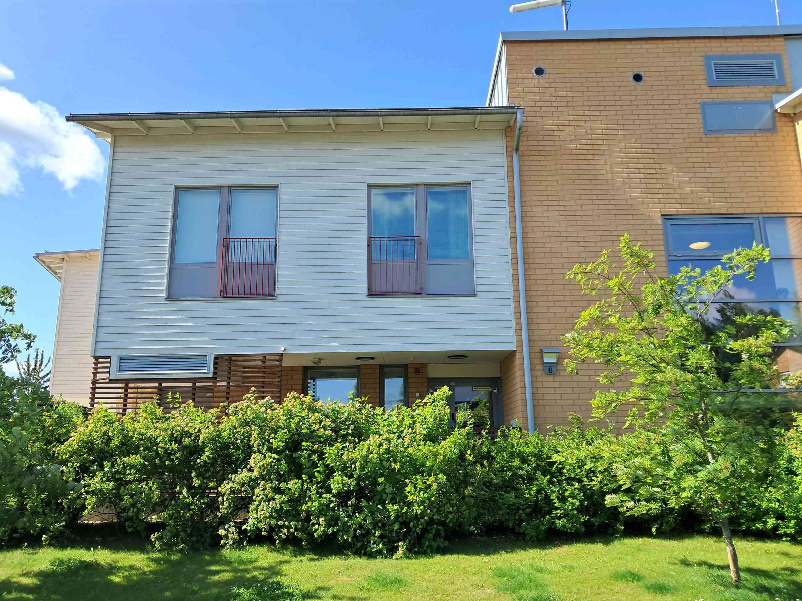 Yksikkö ulkoa päin. Vaalea rakennus, isot ikkunat